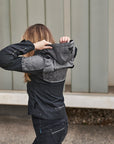A woman putting a hood of a grey motorcycle jacket  from shima