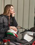 A thinking woman leaning on her motorcycle wearing grey women's motorcycle jacket from SHIMA