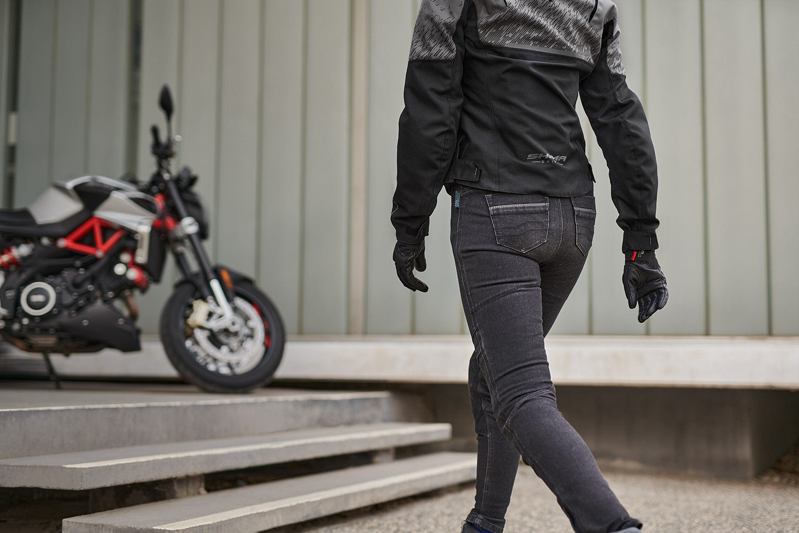 a woman walkig towards her motorcycle wearing grey women&#39;s motorcycle jacket from SHIMA