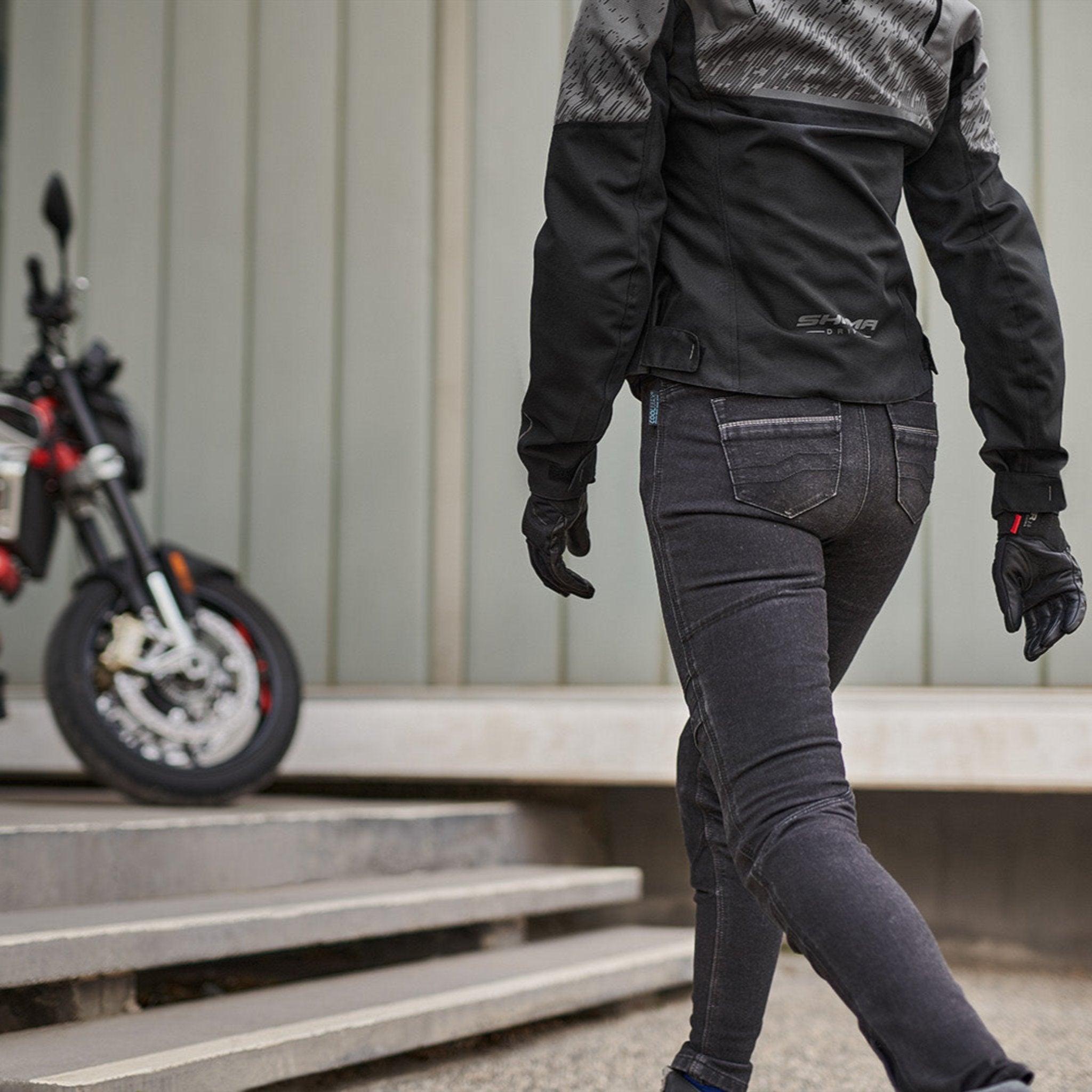 a woman walkig towards her motorcycle wearing grey women&#39;s motorcycle jacket from SHIMA