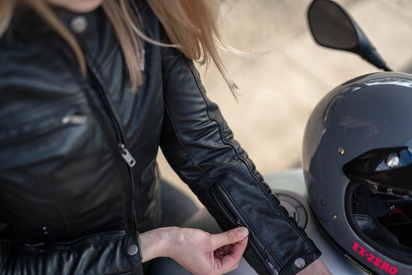A woman closing a zipper of her black motorcycle jacket sleeve