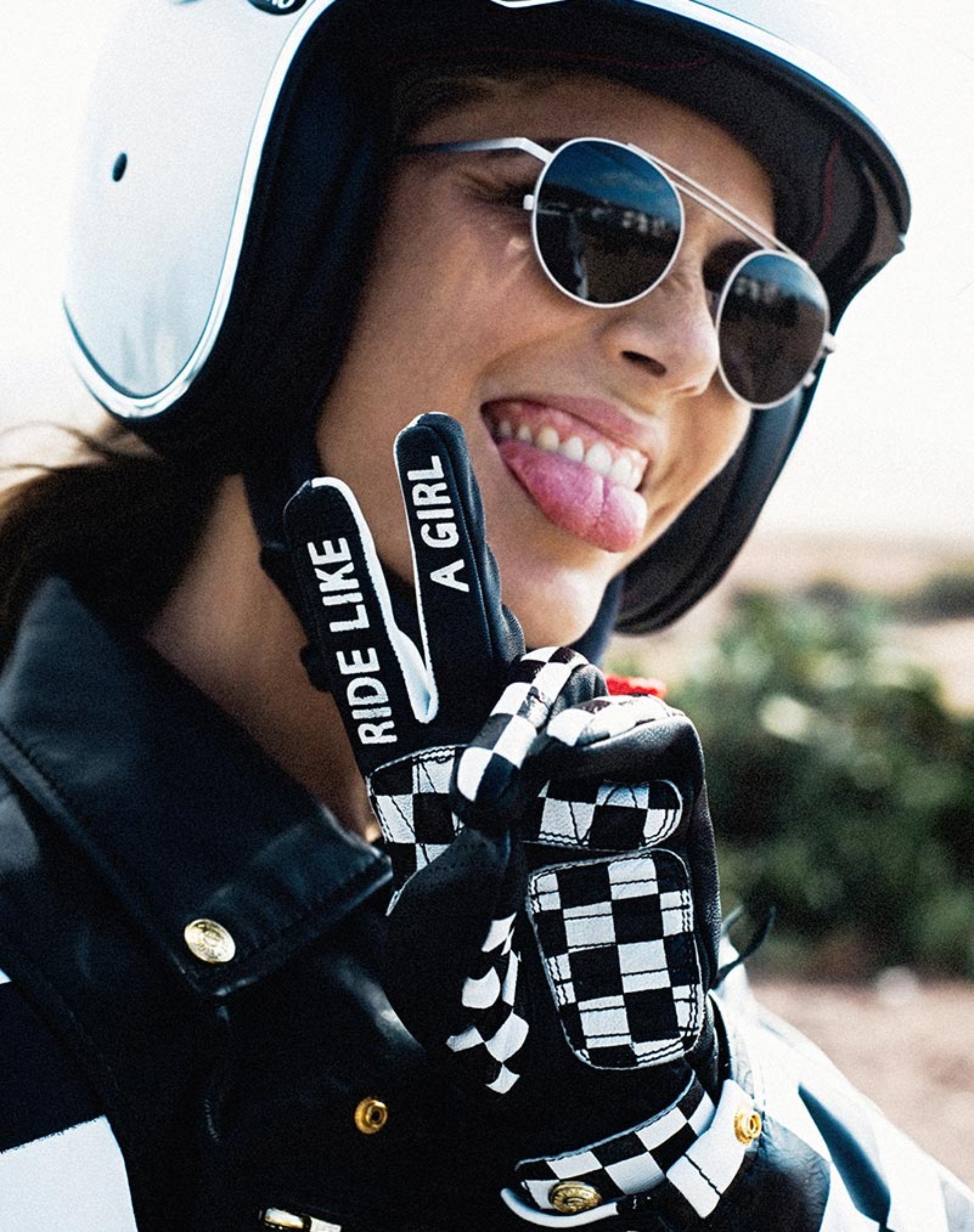 A woman showing peace hand gesture with Ride like a girl words on her motorcycle gloves 