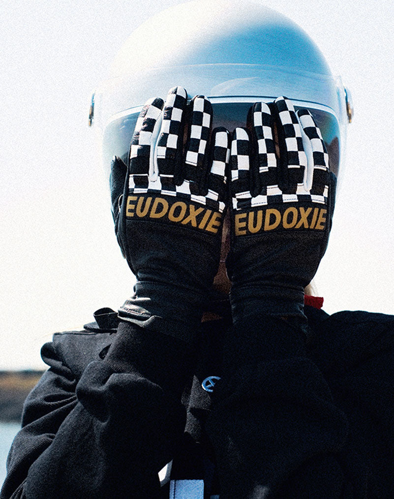 A woman covering her face with her palms, wearing Black and white chessboard motives women&#39;s leather motorcycle gloves from Eudoxie