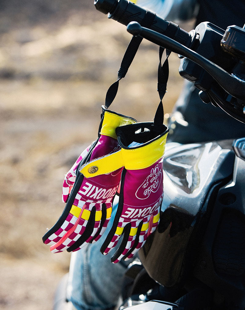 Ride like a Girl pink, black and yellow women&#39;s motorcycle gloves from eudoxie hanging on a motorcycle 