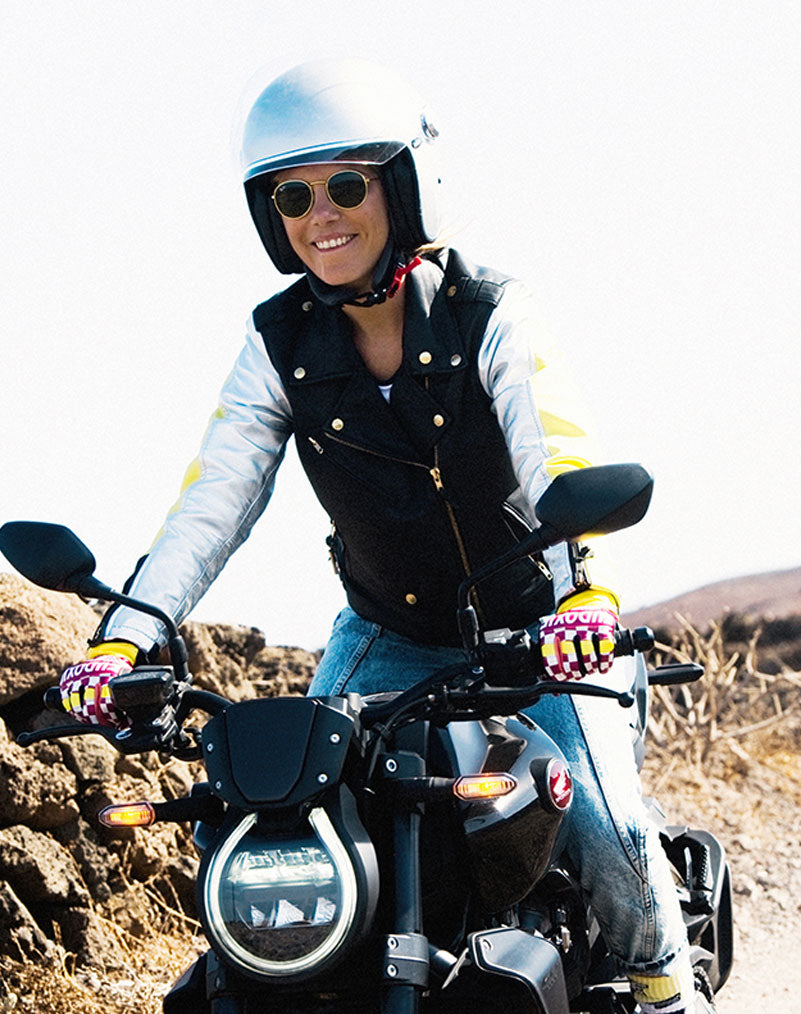 A young happy woman riding a motorcycle and wearing Ride like a Girl pink, black and yellow women&#39;s motorcycle gloves from eudoxie