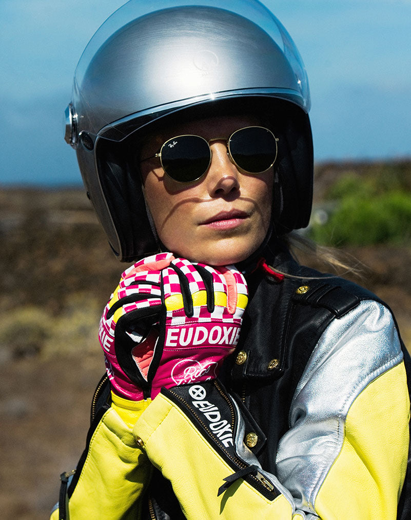 A woman putting on her helmet wearing Ride like a Girl pink, black and yellow women&#39;s motorcycle gloves from eudoxie