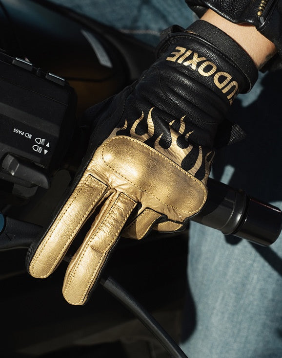 Woman&#39;s hand on a throttle wearing black Eudoxie mc glove with golden flames 