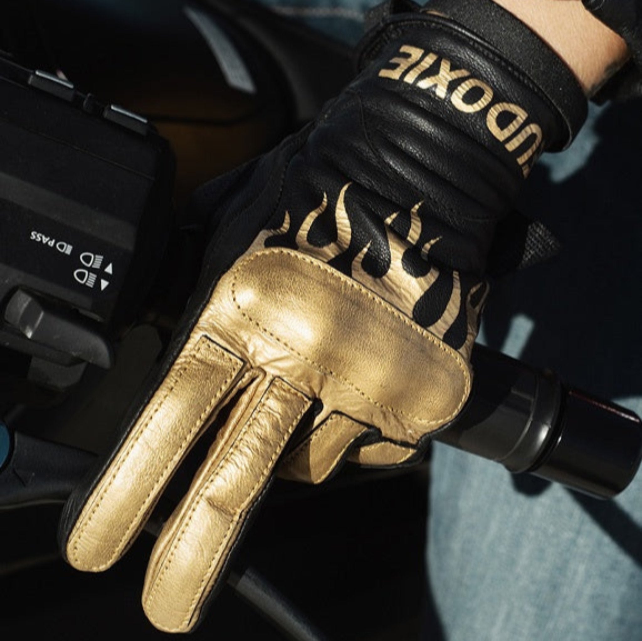 Woman's hand on a throttle wearing black Eudoxie mc glove with golden flames 