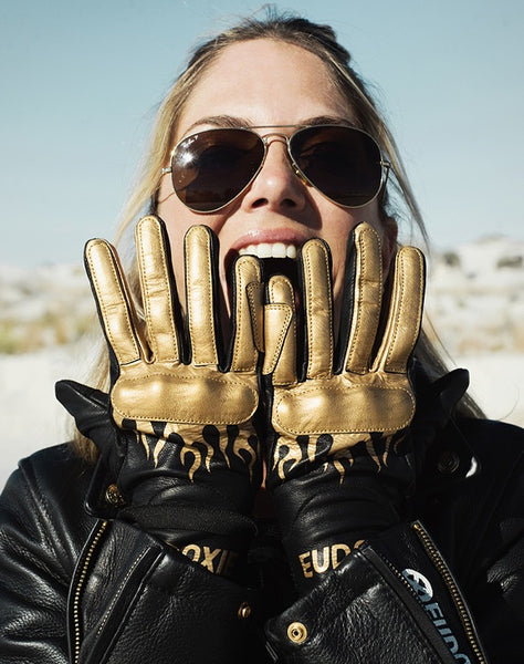 Woman holding her hands in front of her face wearing black Eudoxie mc glove with golden flames 