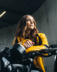 En ung kvinde på sin motorcykel iført en gul motorcykeljakke til damer