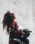 En ung kvinde på sin motorcykel iført en rød motorcykeljakke til damer