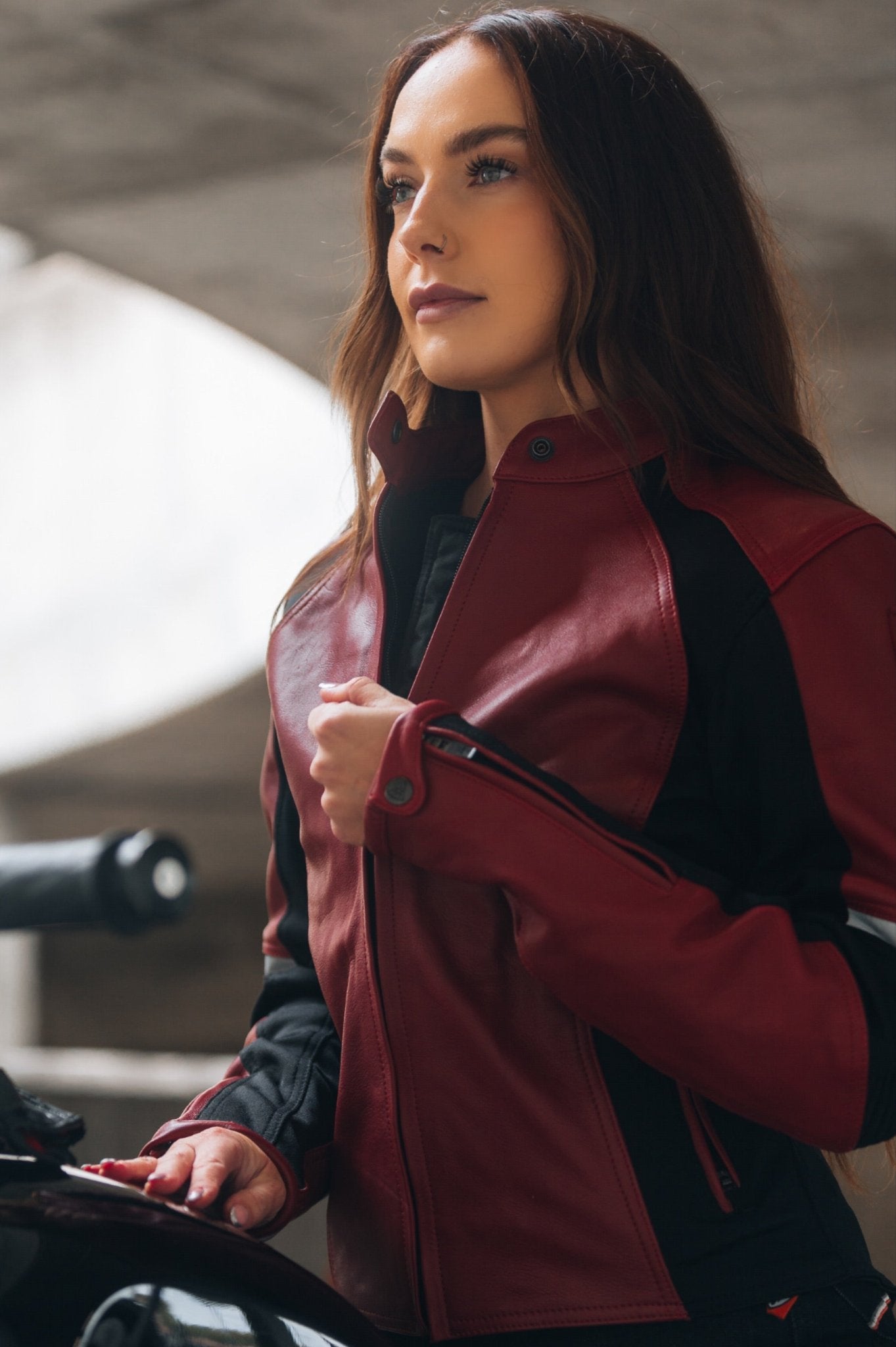 A young woman on her motorcycle wearing a red and black women&#39;s motorcycle jacket