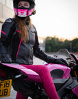 A woman wearing pink motorcycle trousers on a motorcycle 