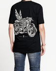 A woman wearing Pando Moto motorcycle t-shirt with the picture of a motorcycle with wings and title that says "going places"
