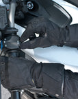 A woman's hand wearing Black long waterproof women's motorcycle glove and switching light on the handle bar of the motorcycle